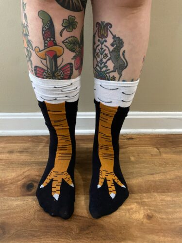 Person wearing chicken leg socks with tattoos on their legs.